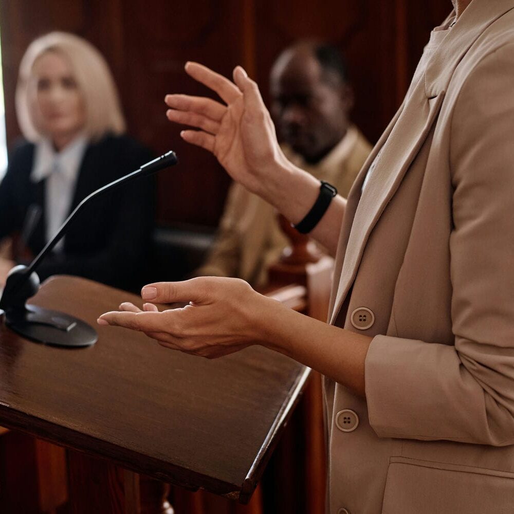 Expert witness testifying at a courtroom podium before judge and counsel, representing life care planning testimony in class action and mass tort proceedings
